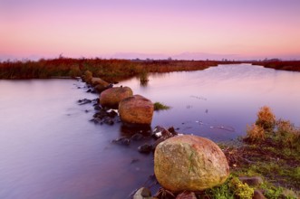 Big stones on wide river at colorful sunrise