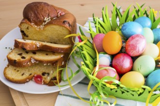 Still life with Nice spring yellow flowers, colorful Easter eggs and traditional Easter cake