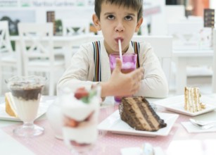 Child drink lemonade. Cake and a milkshake in confectionery