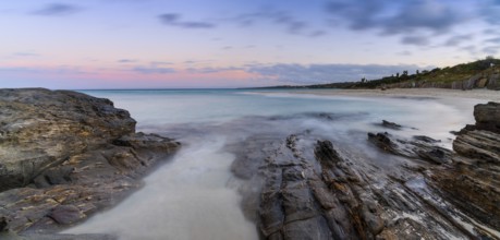 Colorful sunset over the picturesque white sand beach and turquoise waters at La Pelosa Beach