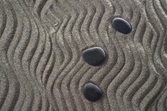 Drawings on light gray sand and black stones in a small Zen garden
