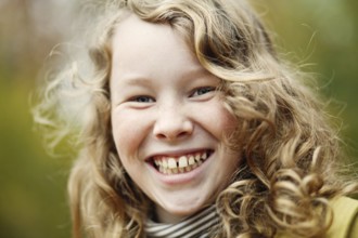 Outdoor portrait of smiling blond girl in autumn park, Belgium, Europe