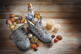 Boots filled with sweets, chocolate Santa and Christmas decoration on a wooden background with