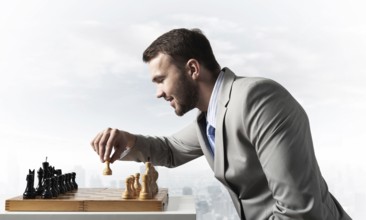 Concentrated businessman playing chess game. Successful management and leadership concept.