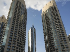 Three modern skyscrapers with glass facades under a bright blue sky, modern skyline with imposing