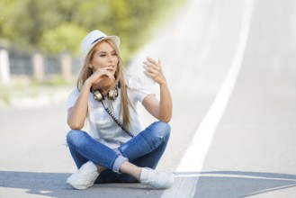 Happy young woman with vintage headphones around her neck, surfing the internet on her smartphone