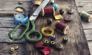 Outdated tools and jewellery for needlework on wooden background