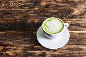 Top view of the cup Matcha latte on wooden background. The concept of green tea as an art