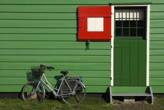 Bicycle parked in front of a green painted timbered house on the Dutch tourist attraction Zaanse