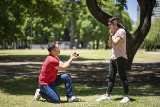 Young man surprising his boyfriend in a park with a wedding ring
