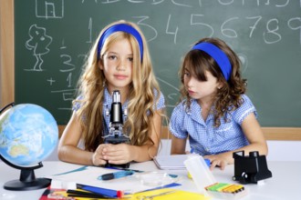 Children girls at school classroom with world map and microscope