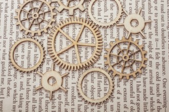 Wooden cogwheels on a page of a book. Industry concept information