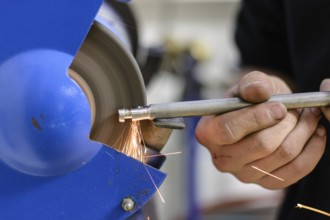 Skilled worker working on metal on a grinding machine - close-up
