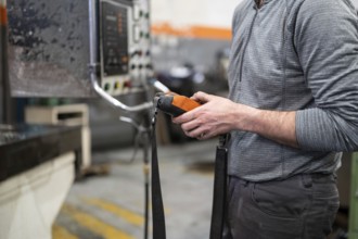 Factory worker. Technician controlling a heavy crane in factory, close up at his hands holding a