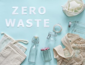 Zero waste concept. Textile eco bags, glass jar and bottle on blue background with Zero Waste white