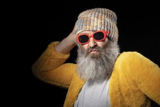 Creative older man with grey beard in fashionable clothes on black background