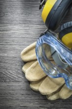 Safety gloves goggles earmuffs on wooden board