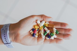 A person holds several medicine pills in his hand