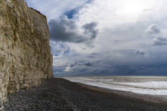 Landscape view of a black rock beach on the Jurassic Coast of England with tall chalkstone cliffs