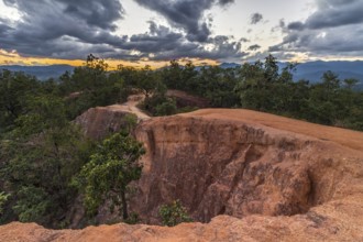 Canyon near Pai city cloudy sky at sunset. Red sandy path and rocky walls. Mae Hong Son province,