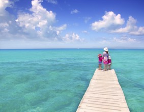 Daughters and mother in jetty on Formentera with turquoise sea