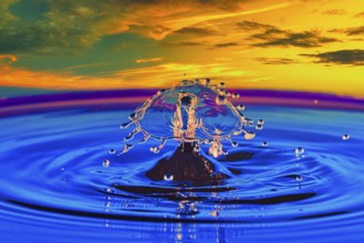 A drop of water in the middle of a lake with a colourful sunset in the background, highspeed