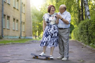Happy elderly couple with a skateboard. Handsome man and woman seniors. Husband and woman in old