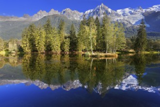 Dreamlike beauty lake and park. In smooth water reflected snow-capped mountains surrounding the