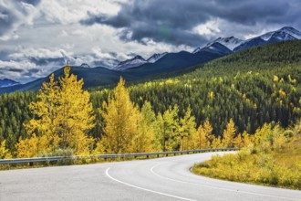 Gorgeous stormy sky in October. Road among autumn forest. Rocky Mountains of Canada
