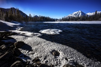 Snowy lake with mountains and forest under a clear blue sky, Yukon, Canada, North America