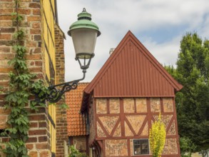 Historic lantern in front of a half-timbered house and green plants on a sunny day, ystad, sweden,