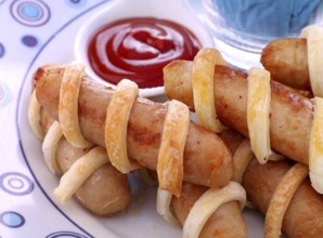 Fresh baked twisted pastry around chicken sausages with ketchup