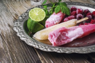 Popsicles served with raspberries and lime on a metal tray.selective focus
