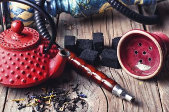 Details of Smoking hookah and red metal kettle spilled tea leaf