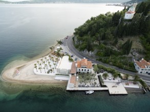 Cozy hotel on a green cape with a beach and a pier. Lepetane, Montenegro. Drone.