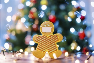 Gingerbread man in a protective icing mask on the table in the light of multi-colored lights on the