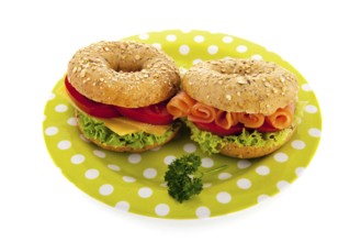 Fresh bagels with cheese, vegetables and fish isolated over white background