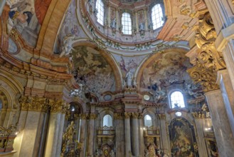 Ornate baroque church interior adorned with frescoes, statues, and warm-colored arches, St.