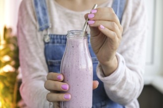 Female hands holding Blueberry smoothie topped with blueberries. Woman eating glass of breakfast