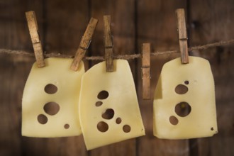 Presentation of slices of Swiss cheese Emmentaler hanging by a thread