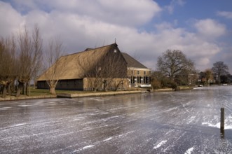 Frozen river the Graafstroom with on the other side a monumental farm in the South Holland village