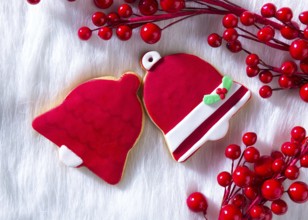 Christmas cookies Xmas red bell shape on white fur background