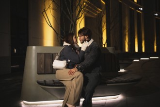 Close couple talking intimately on a bench at night in a city setting
