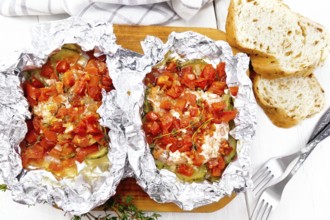 Pink salmon with zucchini, tomatoes, onions, garlic and thyme, baked in foil, fork and bread on the