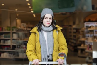 Woman in winter clothes shopping with a shopping trolley on foot, mobility, environmentally