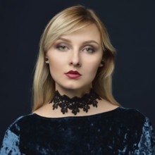 Portrait of the beautiful blonde woman in the blue velvet dress. Shooting in the studio with a dark