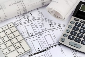 An architect's construction plan with a calculator. Symbolic photo for financing and planning a new