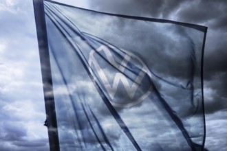 VW sign on the flag of a car dealer in front of a dark sky, symbolic photo VW crisis, photomontage