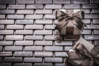Presents wrapped with brown ribbons on wooden mat holidays concept