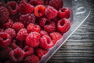 Red raspberry in container on wooden board